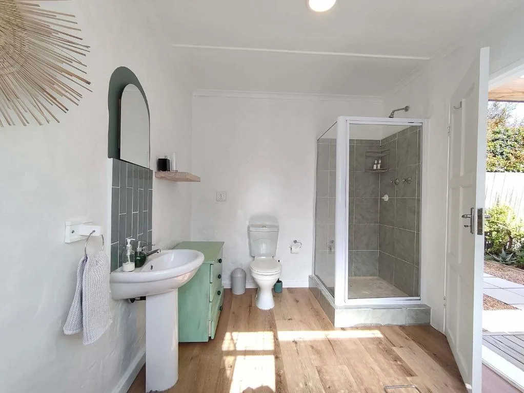 Modern bathroom with pedestal sink, toilet, and walk-in shower enclosure