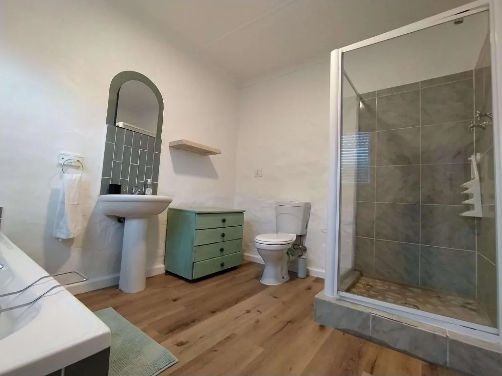Modern bathroom with pedestal sink, toilet, and large tiled shower enclosure