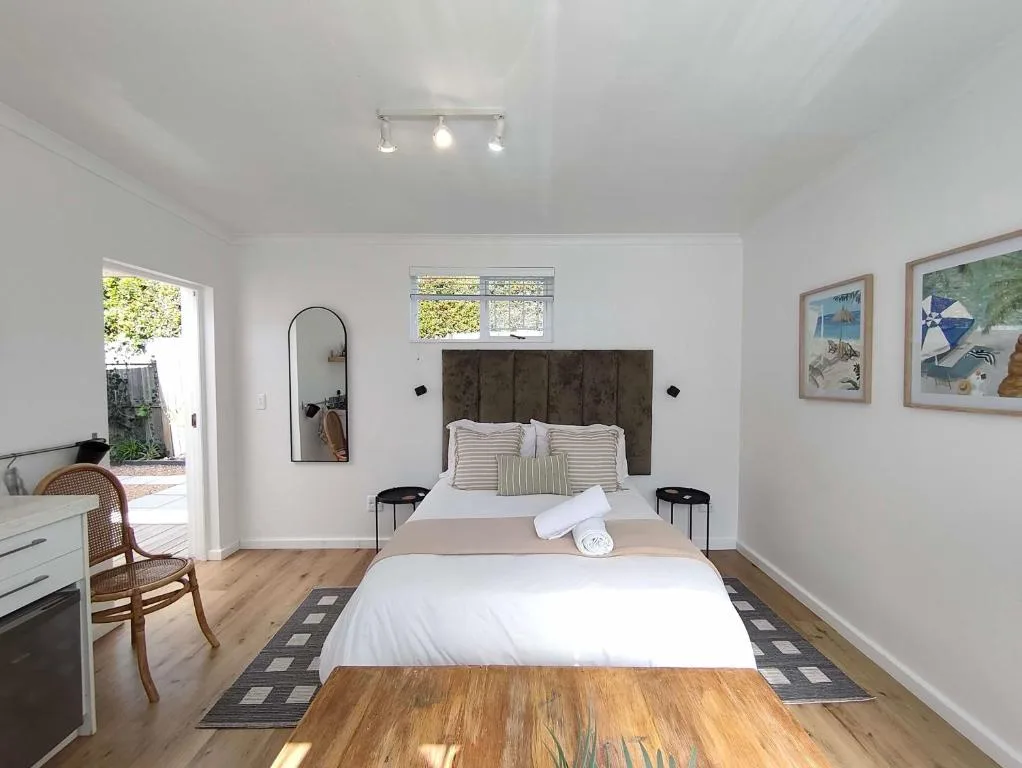 Bright bedroom with dark headboard bed, wooden floors, and garden access
