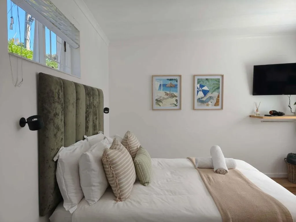 Bright bedroom with green upholstered headboard and coastal-themed wall art
