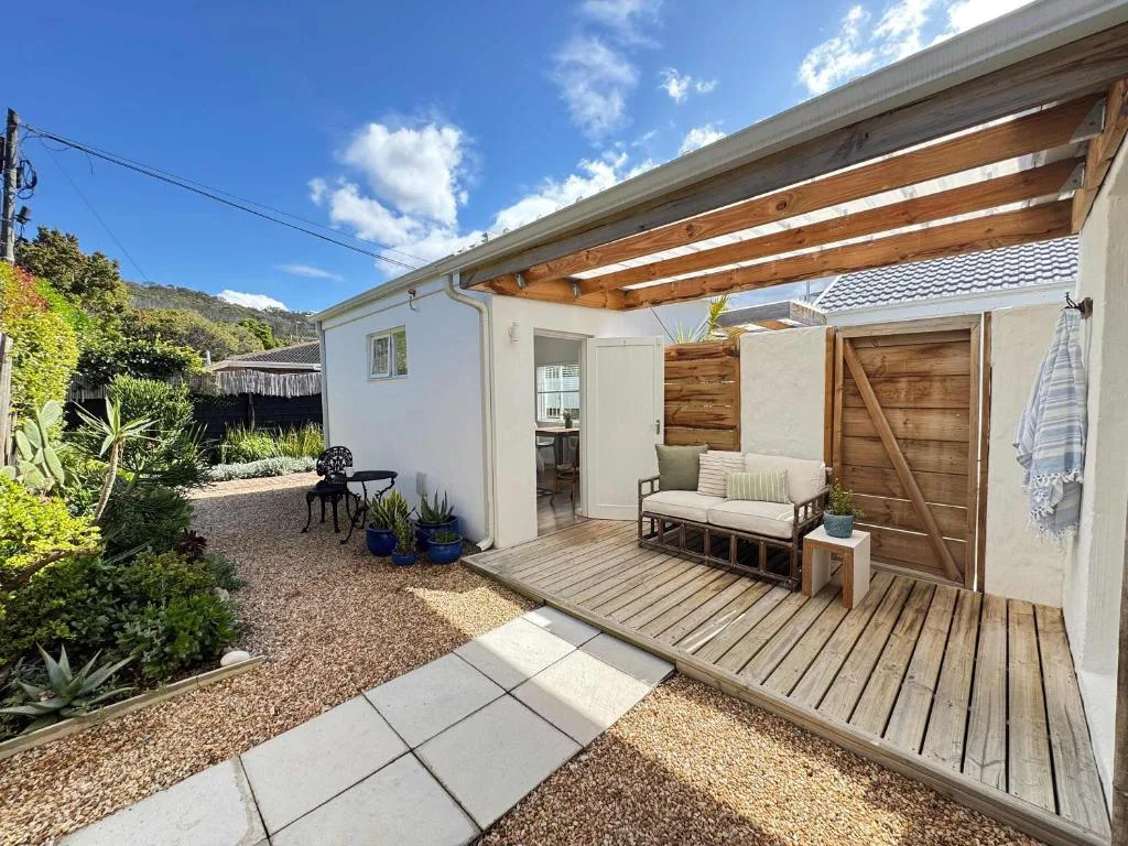 Wooden deck with pergola, seating area, and garden surroundings