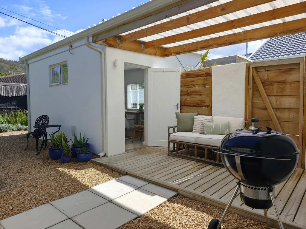 Wooden deck with braai, lounge seating, and modern white apartment exterior