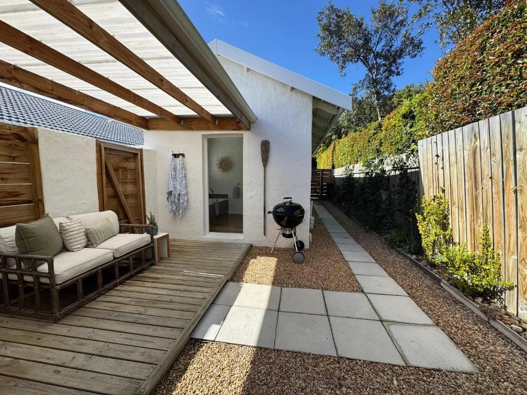 Modern patio with wooden pergola, seating area, and braai grill