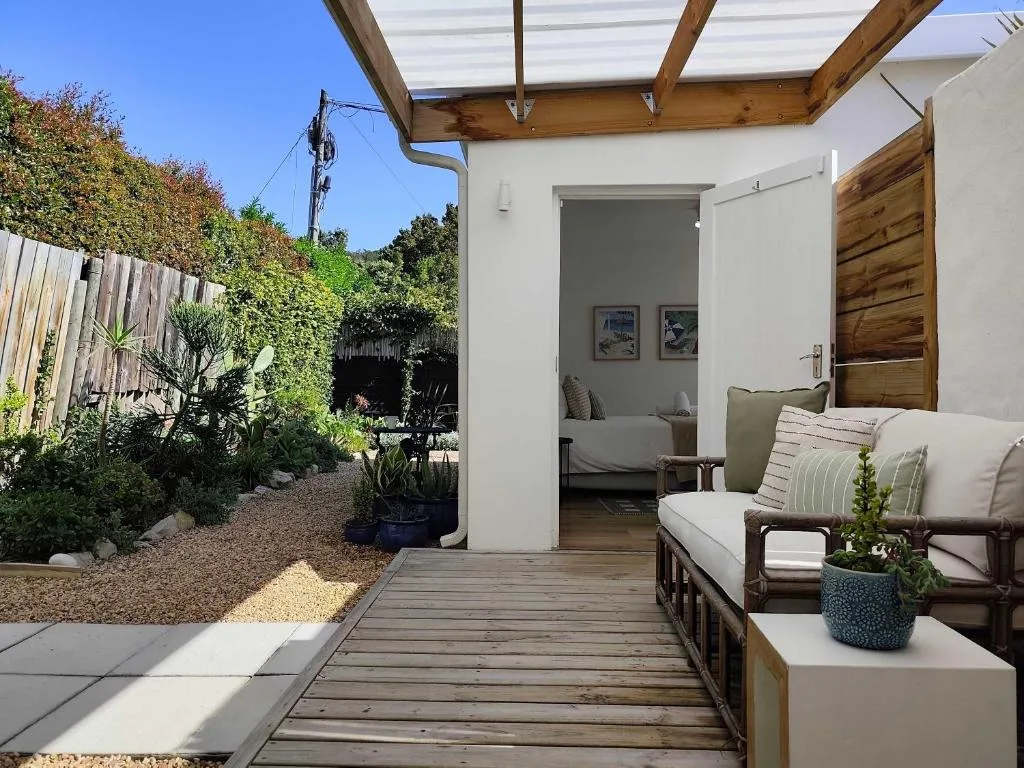 Covered wooden deck with outdoor seating, garden, and interior access door