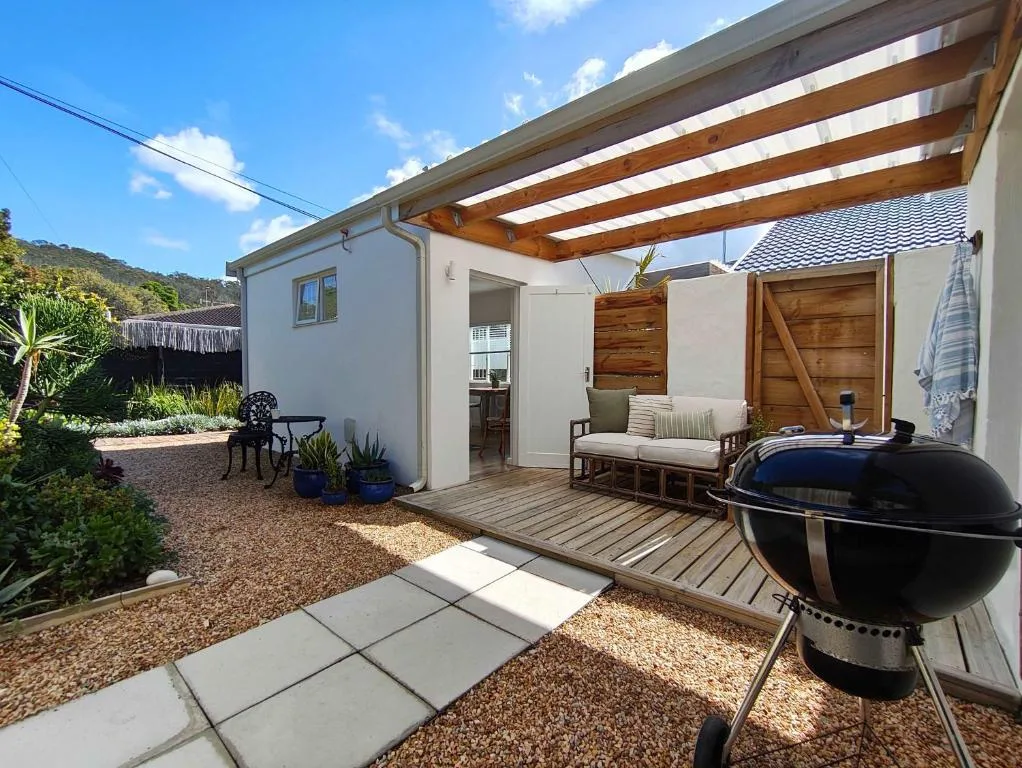Wooden deck with pergola, seating, and braai area overlooking garden