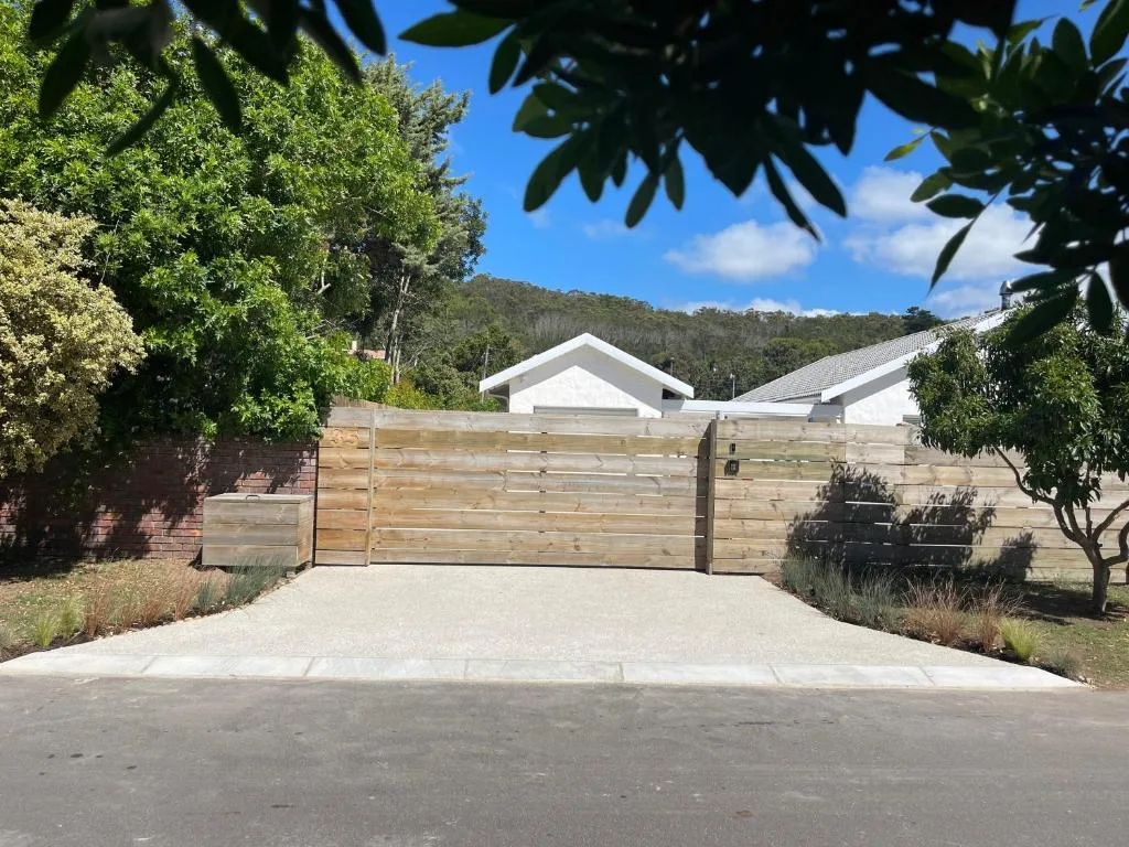 Modern white house with wooden gate and forested mountain backdrop