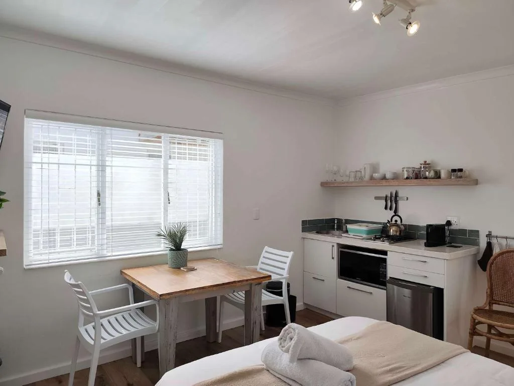 Modern kitchen with white cabinetry, black stovetop, and wooden dining table