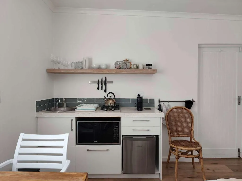 Modern kitchenette with white cabinetry, dark tile backsplash, and stainless steel appliances
