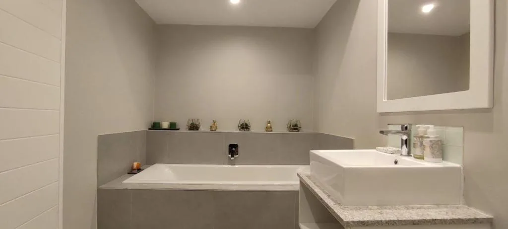 Modern bathroom with soaking tub, dual vanity sink, and illuminated mirror