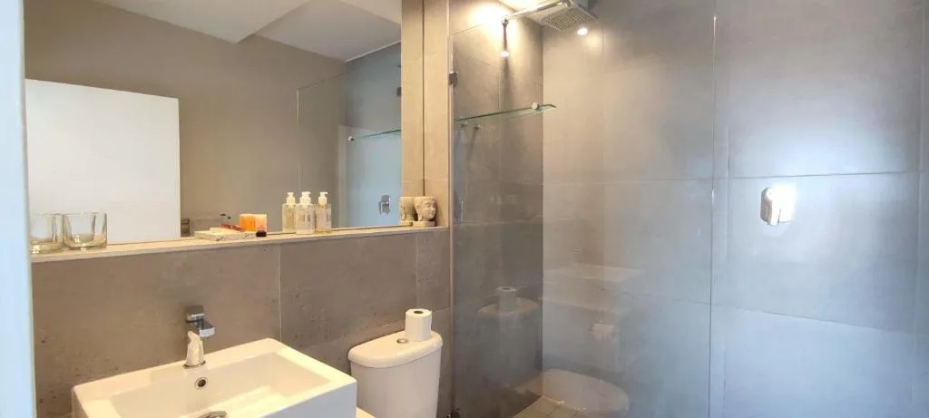 Modern bathroom with vanity sink, toilet, and frameless glass shower enclosure