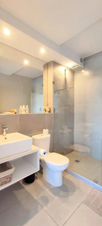 Modern bathroom with white vanity, toilet, and glass shower enclosure