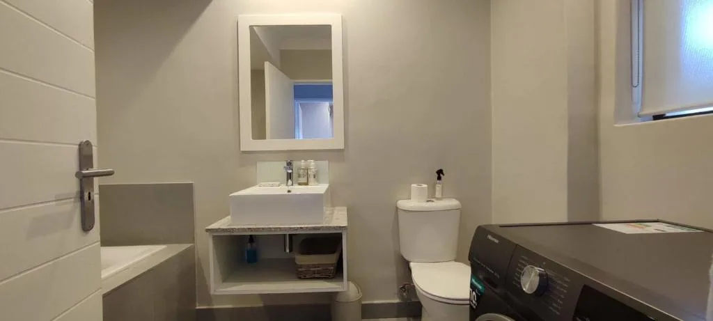 Modern bathroom with white vanity sink, mirror, and toilet fixture