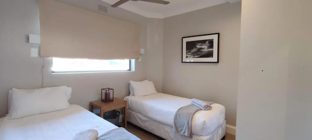 Twin bedroom with white linens, window, and framed artwork on wall