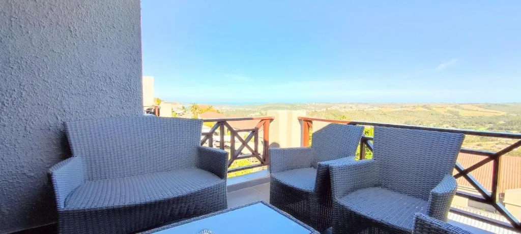 Outdoor seating area with rattan chairs overlooking rolling hills and landscape