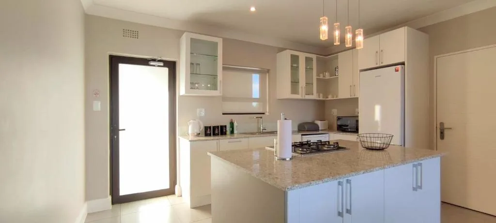 Modern kitchen with granite countertop island, stainless steel appliances, and pendant lighting