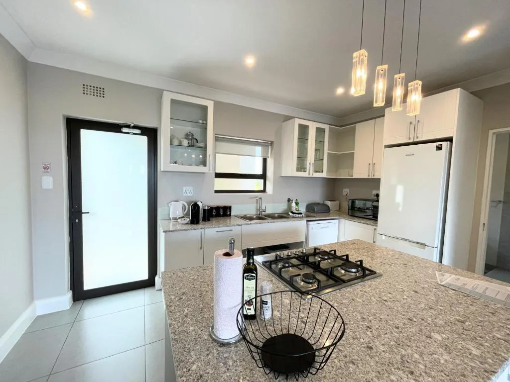 Modern kitchen with white cabinetry, granite countertop, gas cooktop, and stainless steel appliances