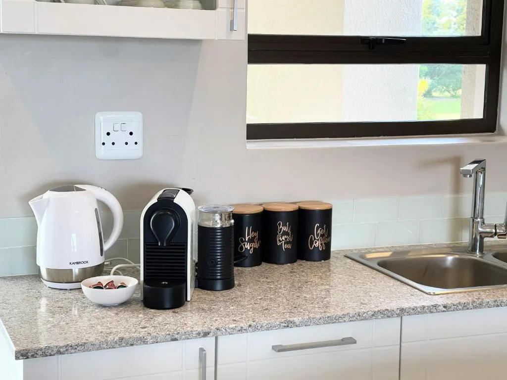 Modern kitchen counter with kettle, coffee machine, storage containers, and sink
