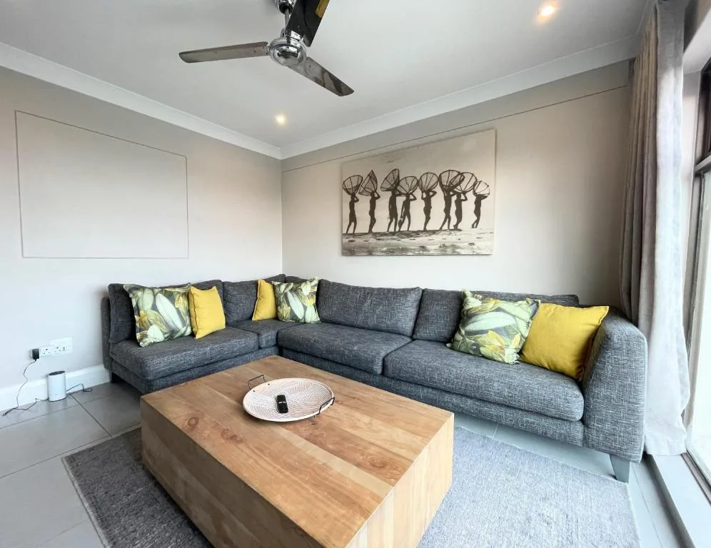 Modern lounge with dark gray sectional sofa, yellow cushions, wooden coffee table
