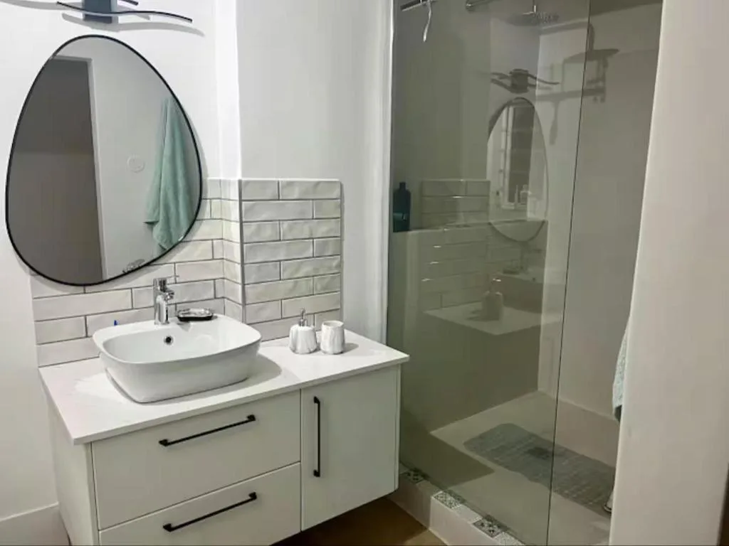 Modern bathroom with round mirror, vessel sink, and glass shower enclosure