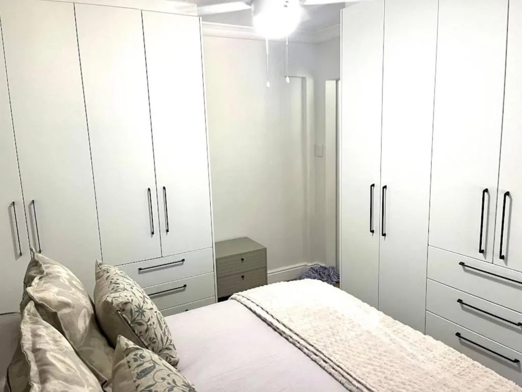 Modern bedroom with queen bed, white built-in wardrobes, and contemporary lighting