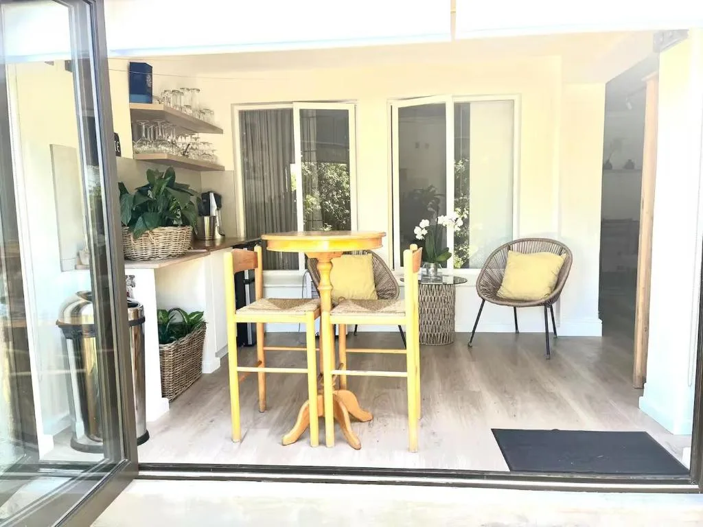Bright yellow bistro table and woven chairs on covered patio with potted plants