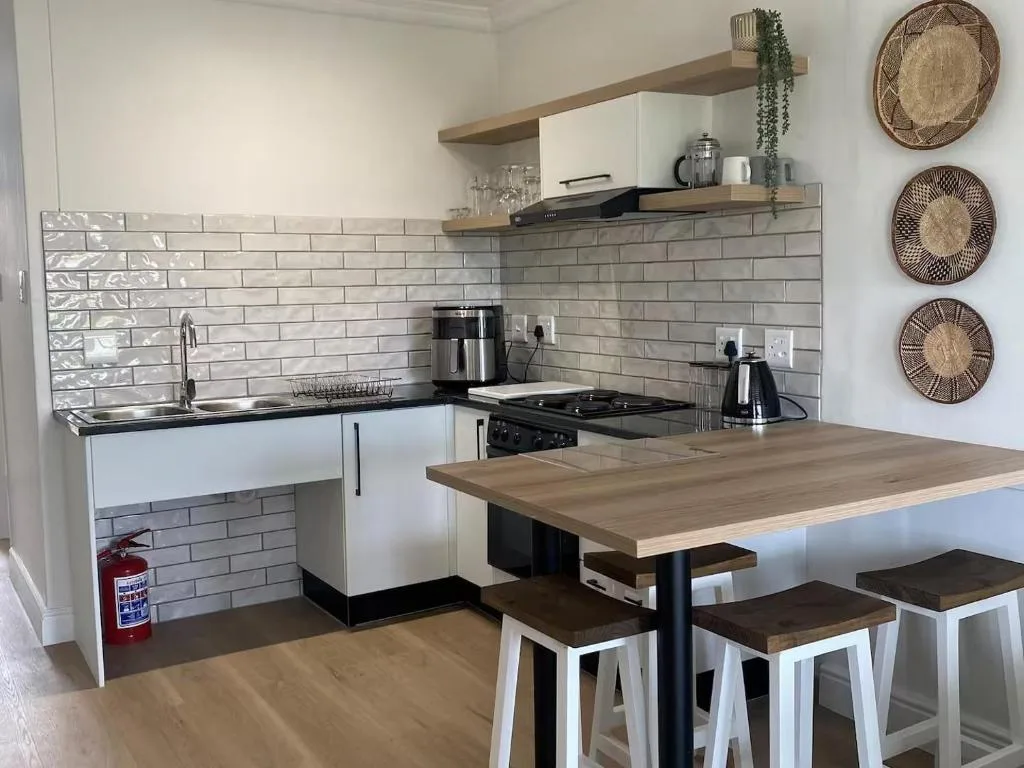 Modern kitchen with white cabinetry, subway tile backsplash, and wooden countertop dining area