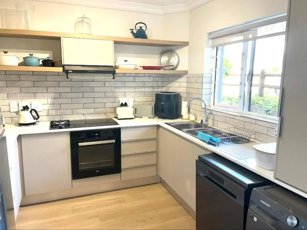 Modern kitchen with white cabinetry, black oven, and open shelving with decor