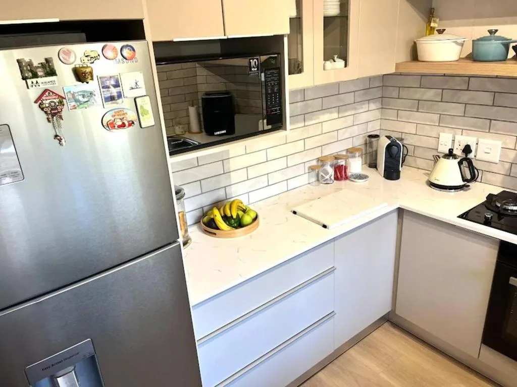 Modern kitchen with white cabinetry, stainless steel fridge, and subway tile backsplash