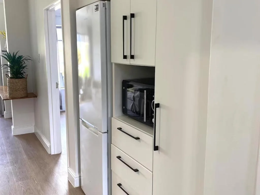 Modern white kitchen with stainless steel refrigerator and microwave oven