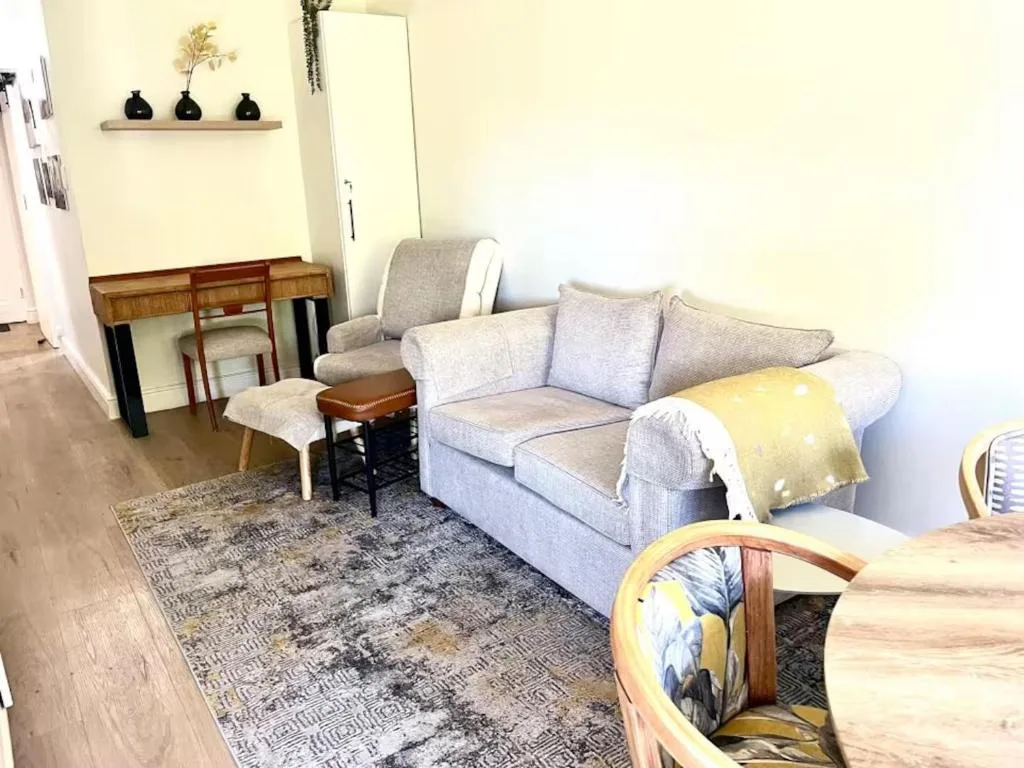 Spacious lounge with gray sofa, armchair, and wooden desk furniture