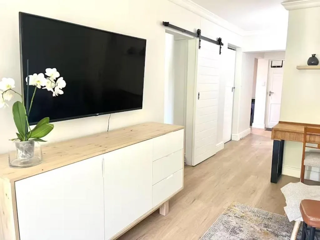 Modern lounge with wall-mounted TV, white storage unit, orchid decor