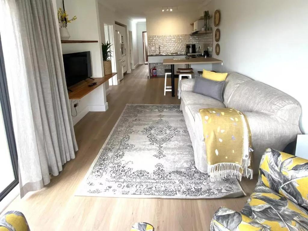 Open-plan living room with comfortable sofa, fireplace, and modern kitchen visible