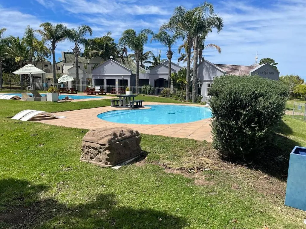Bright blue swimming pool surrounded by manicured gardens and palm trees