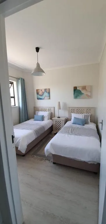 Bright twin bedroom with matching beds, wooden headboards, and pendant lighting