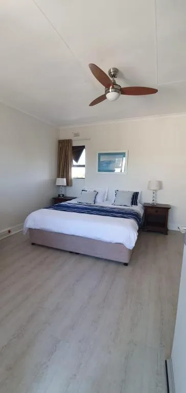 Spacious bedroom with queen bed, ceiling fan, and natural light from window