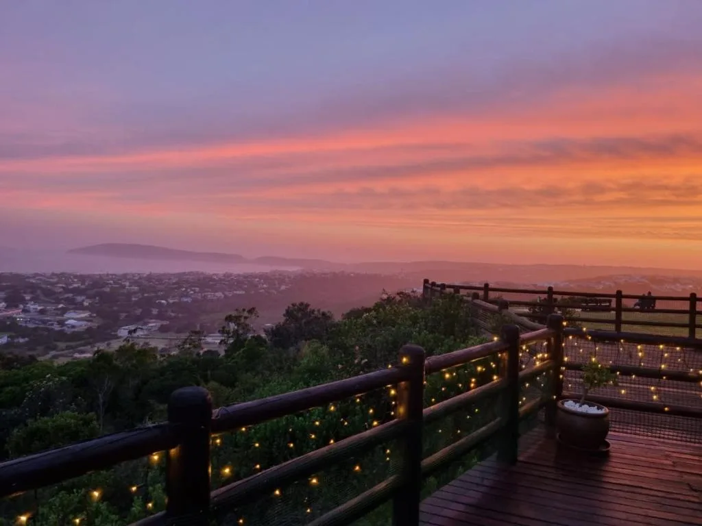 Illuminated wooden deck railing overlooking sunset valley landscape