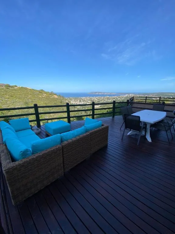 Spacious deck with blue outdoor seating overlooking coastal town and ocean
