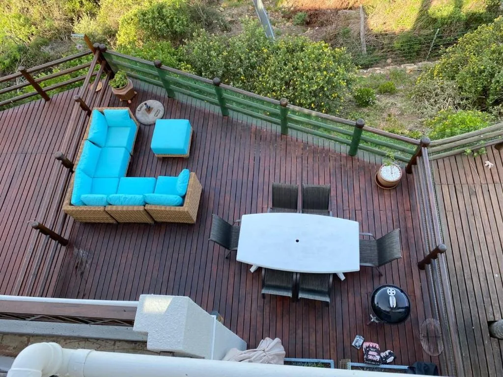 Spacious wooden deck with blue cushioned seating and white dining table