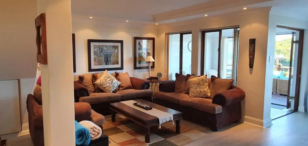 Spacious lounge with brown sofas, framed artwork, and sliding doors to deck