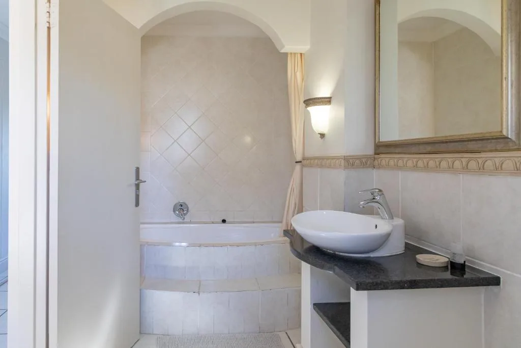 Modern bathroom with curved bathtub, round white sink, and framed mirror