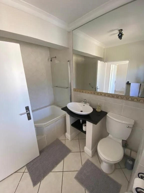 Modern bathroom with white basin sink, toilet, and enclosed shower cubicle