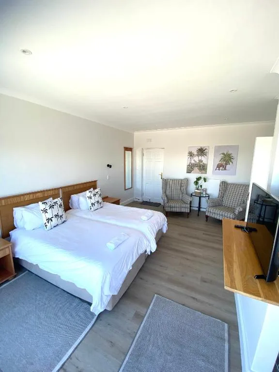 Spacious bedroom with twin beds, wooden headboard, and seating area