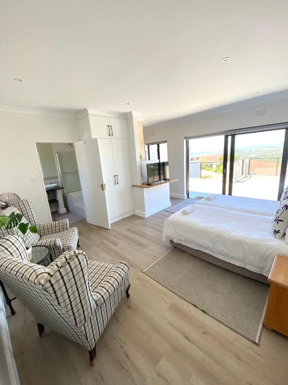 Spacious modern bedroom with double bed, seating area, and garden views