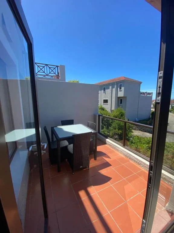 Outdoor terracotta patio with dining table and surrounding white walls