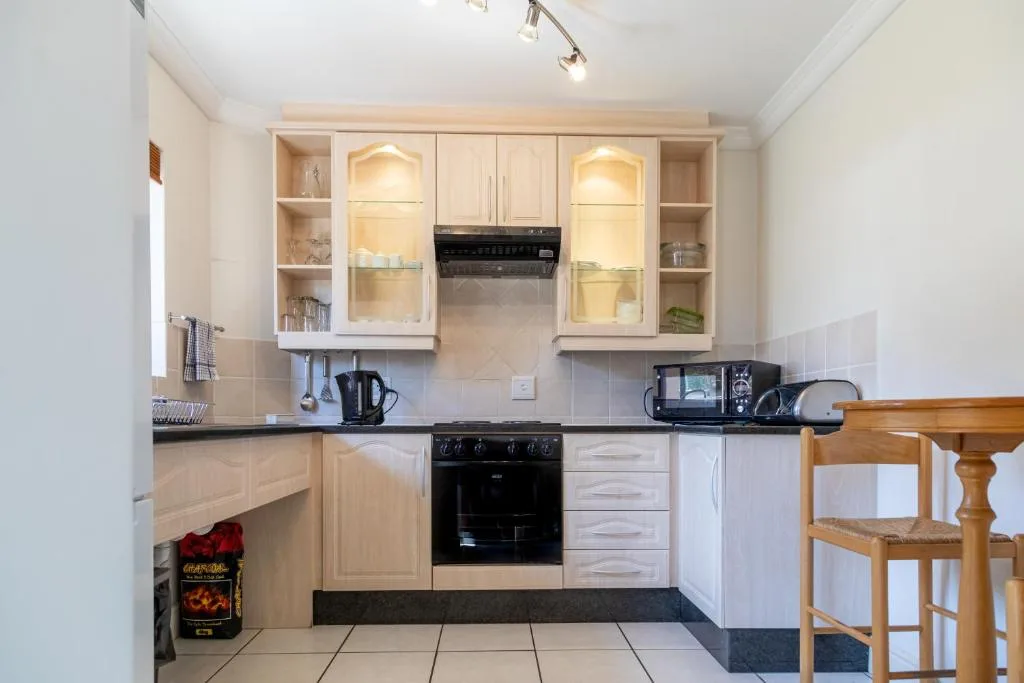 Modern kitchen with cream cabinetry, black appliances, and dark countertops