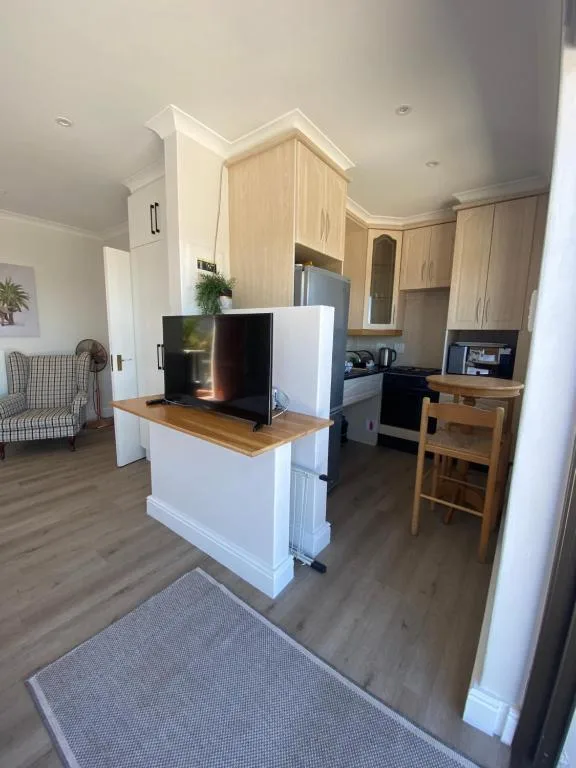 Open-plan living area with TV on wooden island counter and kitchen visible