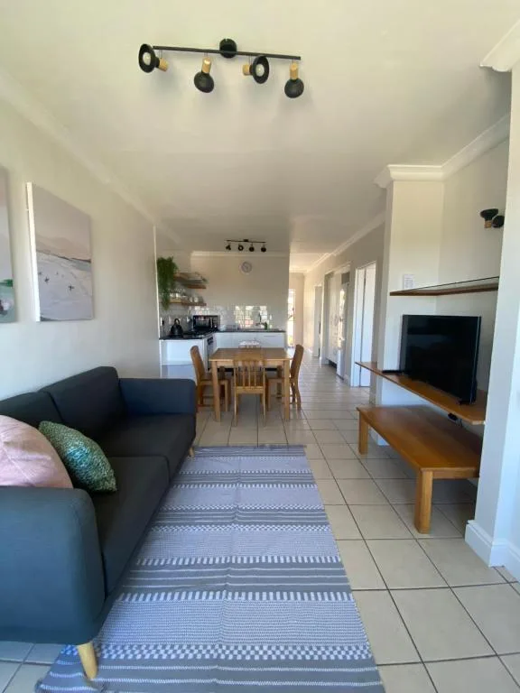 Open-plan living area with black sofa, dining table, and television