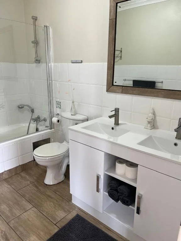 Modern bathroom with double vanity, toilet, and glass-enclosed shower area