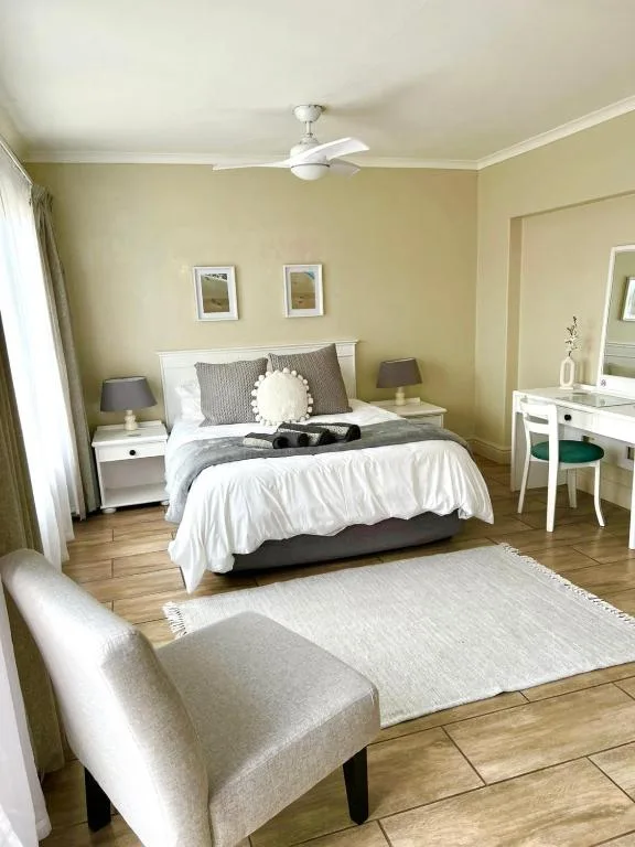 Spacious bedroom with queen bed, white nightstands, and pale yellow walls