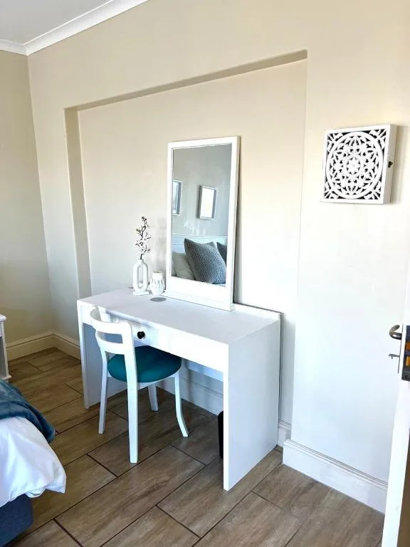 Modern bedroom with white dressing table, mirror, and contemporary decor